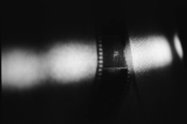 a black and white photo of a film strip, by Adam Chmielowski, obscured underexposed view, anamorphic lens, high angle close up shot, filmposter