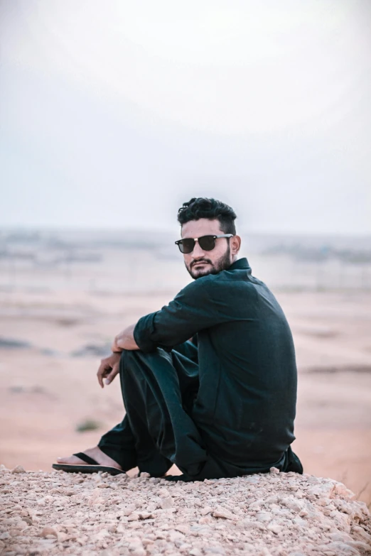 a man in sunglasses sitting on a rock