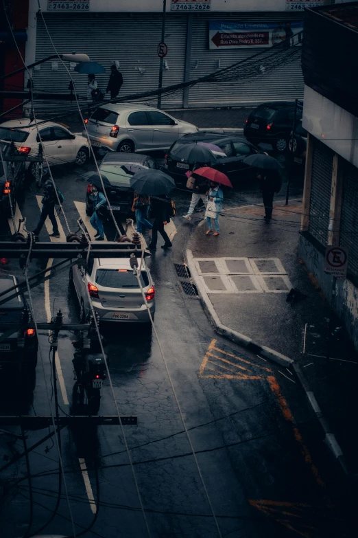 people holding umbrellas walking down the sidewalk in the rain