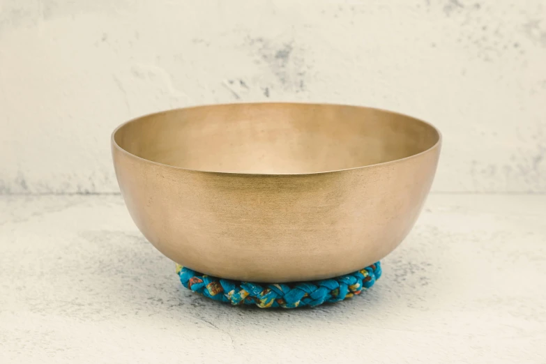 a golden bowl sitting on top of a table, an album cover, by Elaine Hamilton, unsplash, teal cloth, padmasana, bells, set against a white background