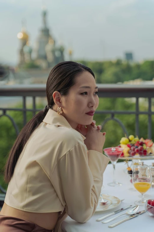 the woman is eating at the table with wine and fruit