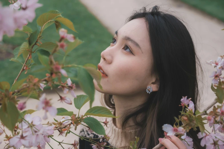 a woman standing in front of a flowering tree, inspired by Huang Ji, trending on pexels, hyperrealism, wan adorable korean face, jewelry, pondering, prominent cheekbones
