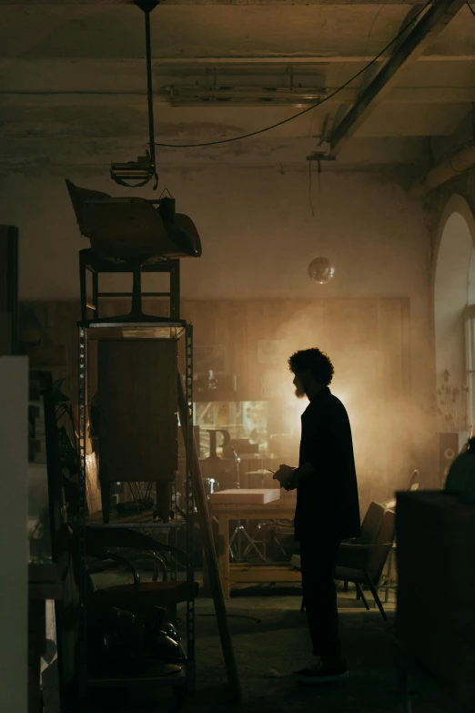 a man standing in a dimly lit room, inspired by casey baugh, pexels contest winner, stands at her easel, denis villeneuve movie still, andrey tarkovsky, robert sheehan