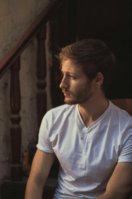 a person sitting on a stair case wearing a white shirt