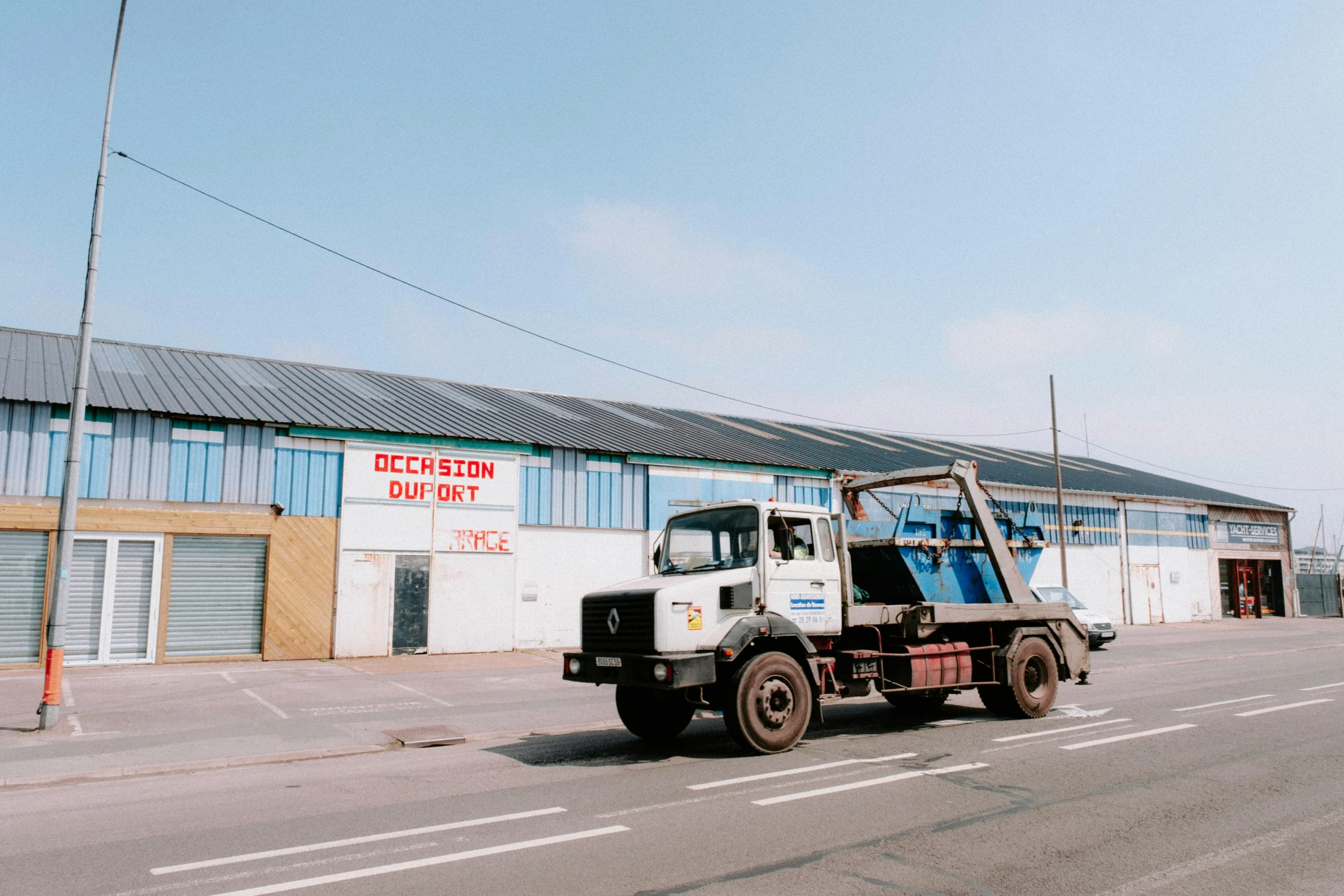 a truck is parked on the side of the road, unsplash, plasticien, scrapyard architecture, 1990s photograph, clear blue skies, commercial banner