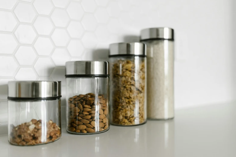 three glass jars filled with nuts on top of a counter, pexels, minimalism, hexagons, stainless steal, small kitchen, 4l