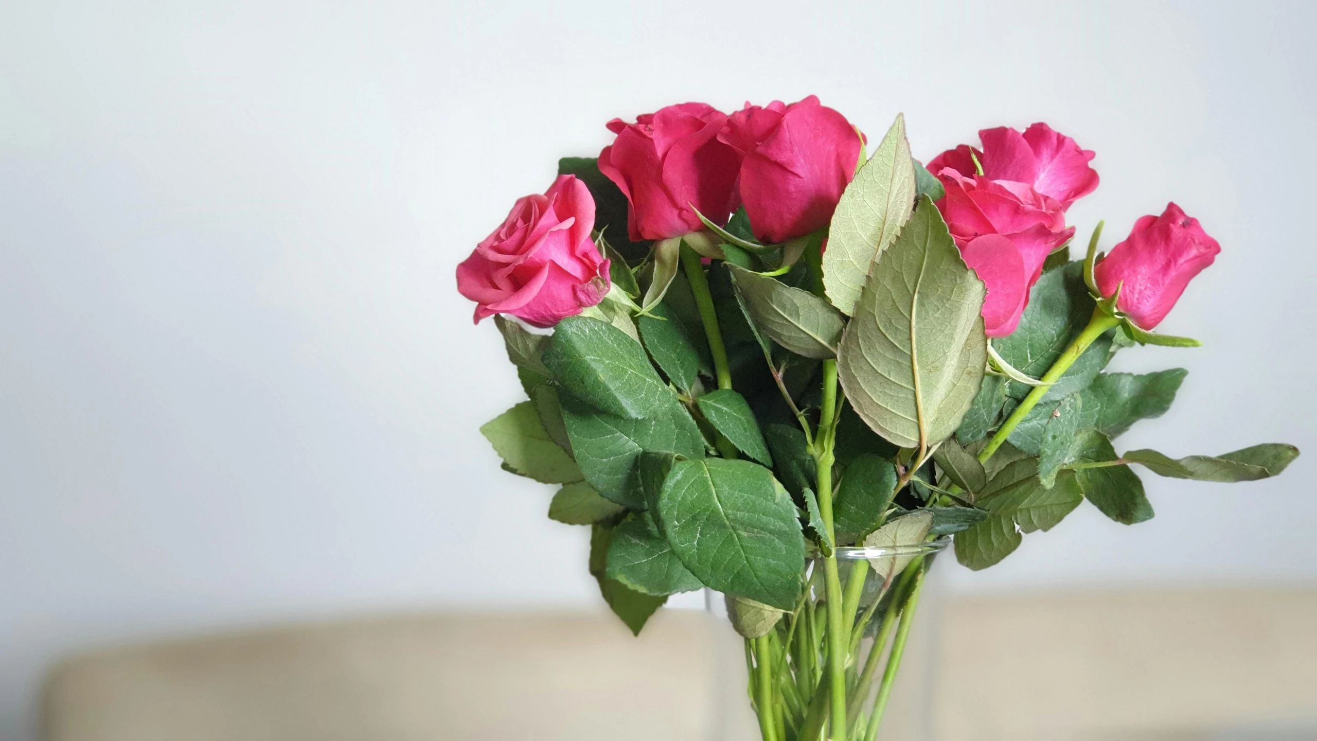 a glass vase full of roses is sitting on the table