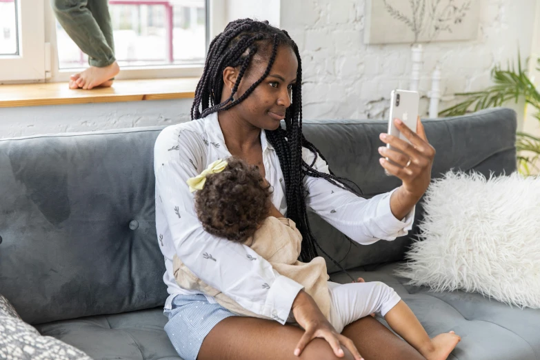 a woman sitting on a couch holding a baby, a picture, pexels contest winner, happening, black teenage girl, hold up smartphone, influencer, brown