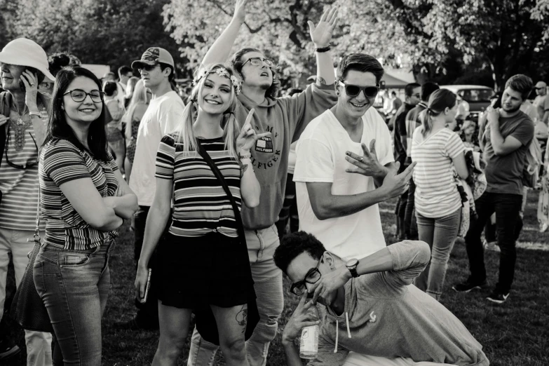 a black and white photo of a group of people, pexels contest winner, happening, summer festival in background, slight nerdy awkward smile, doing a sassy pose, at the park