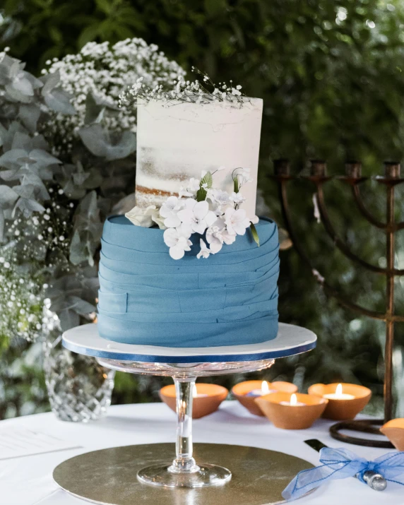 a blue and white cake sitting on top of a table, a picture, slate, grey and blue theme, during the day, botanical rainbow backdrop