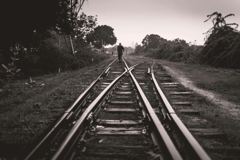 a black and white photo of a person standing on a train track, unsplash, realism, broken down, instagram picture, paths, multiple stories