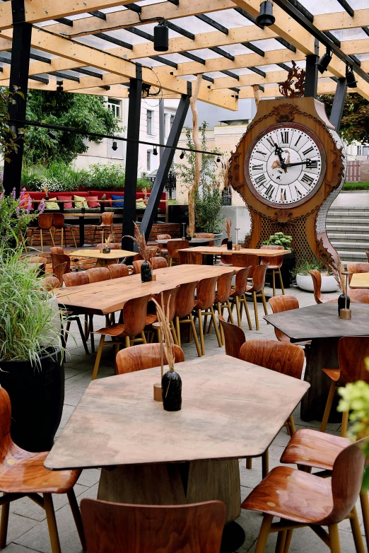 outdoor tables and chairs in an outdoor seating area with a clock hanging over them