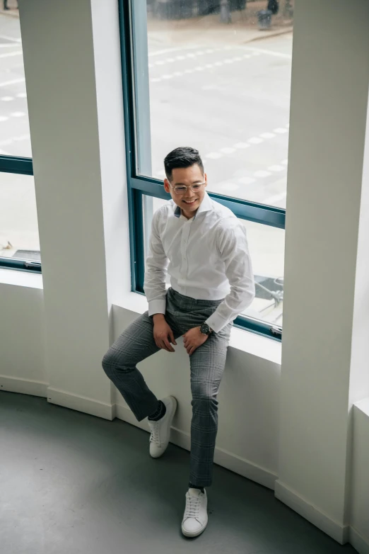a man in a white shirt sitting on a window sill, inspired by Victor Wang, wearing business casual dress, justin sun, in front of white back drop, wearing pants