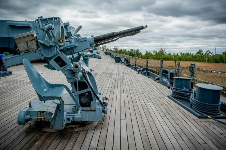 a large machine gun sitting on top of a wooden deck, naval landscape, helsinki, fan favorite, blue