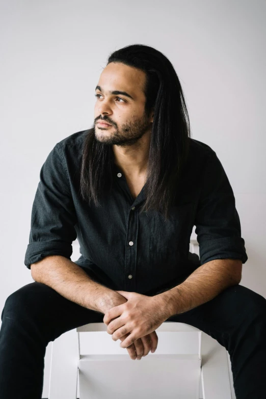 a man with long hair is sitting down