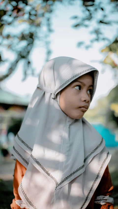 a little girl that is standing in the grass, a colorized photo, by Basuki Abdullah, pexels contest winner, hurufiyya, wearing a grey robe, gif, thoughtful ), school class