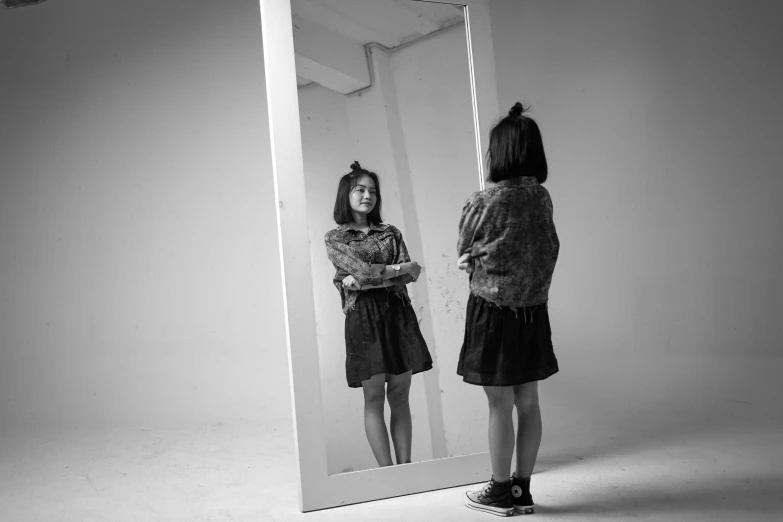 a girl stands in front of a mirror