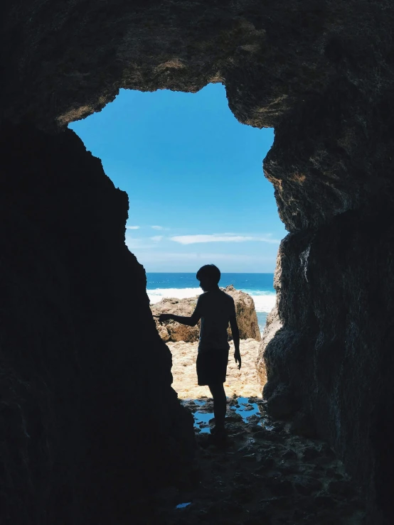 a person standing in a cave looking out at the ocean, boys, profile image