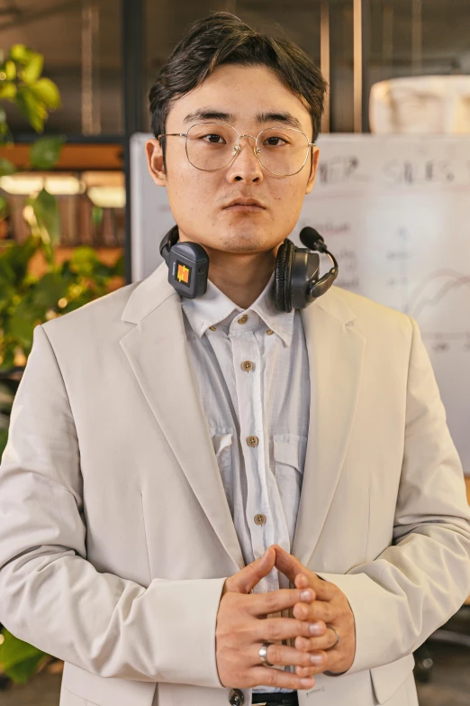 a man wearing headphones standing in front of a poster, by Jang Seung-eop, wearing business casual dress, wearing collar on neck, lofi, subject detail: wearing a suit