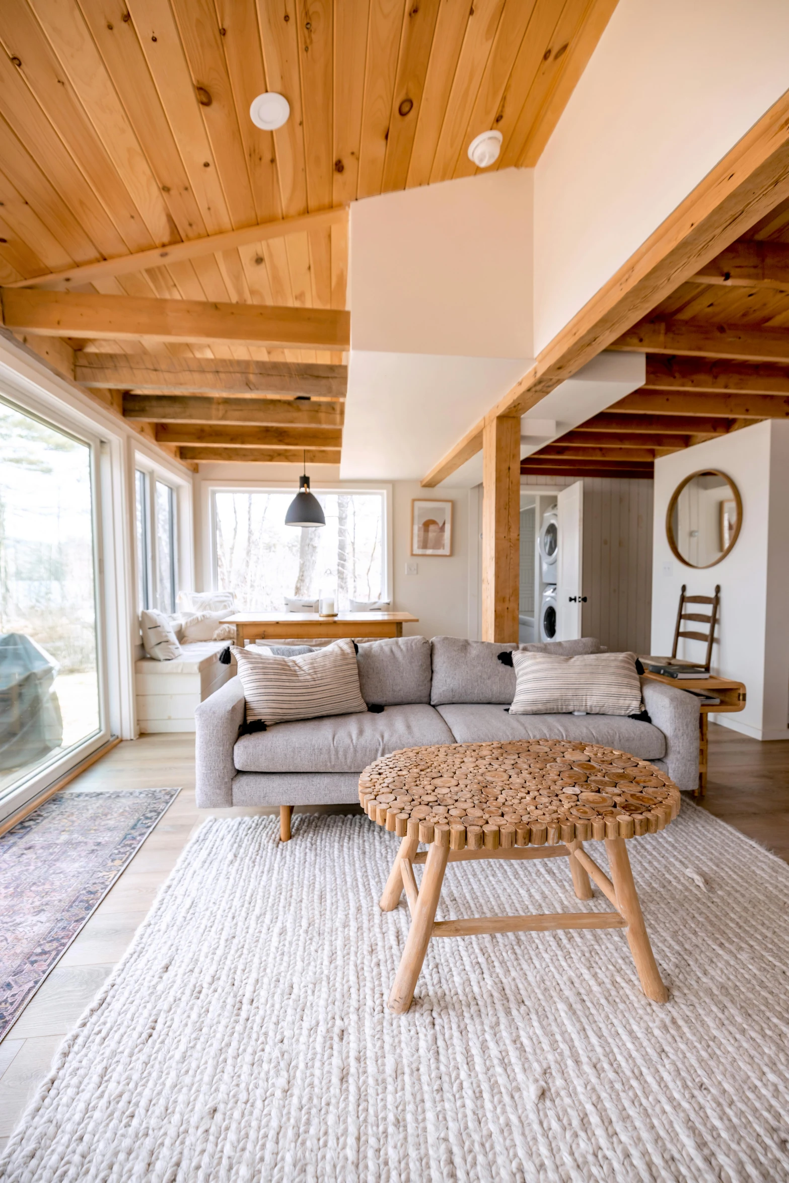 a wood beamed living room features a l shaped couch with low end and an oak coffee table