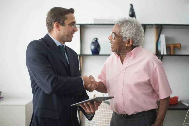 a man in a suit shaking hands with a man in a pink shirt, a photo, pexels contest winner, renaissance, an elderly, wearing a suit and glasses, joseph moncada, holding a staff