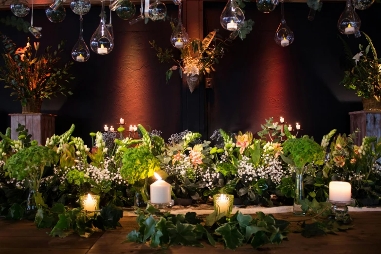 a lot of flowers on a table that have candles on it