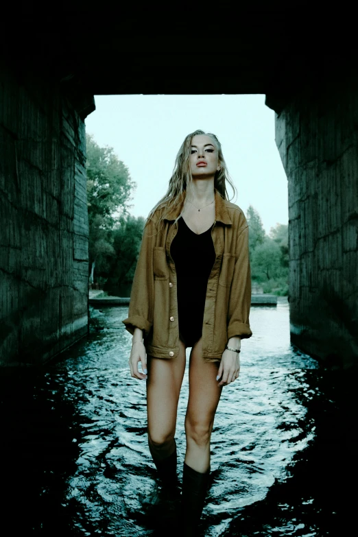 a woman standing in the middle of a body of water, an album cover, inspired by Elsa Bleda, pexels contest winner, sitting under bridge, young blonde woman, caramel. rugged, gif