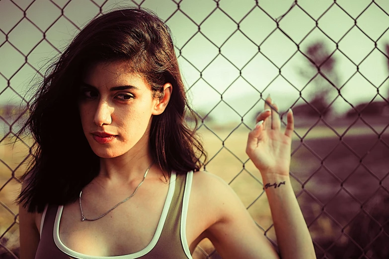 a woman standing in front of a chain link fence, an album cover, inspired by Elsa Bleda, ((portrait)), bralette, annabeth chase, 33mm photo