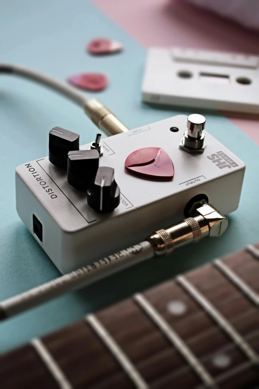 a guitar pedal sitting on top of a blue table, hearts, grey, rose tones, mini model