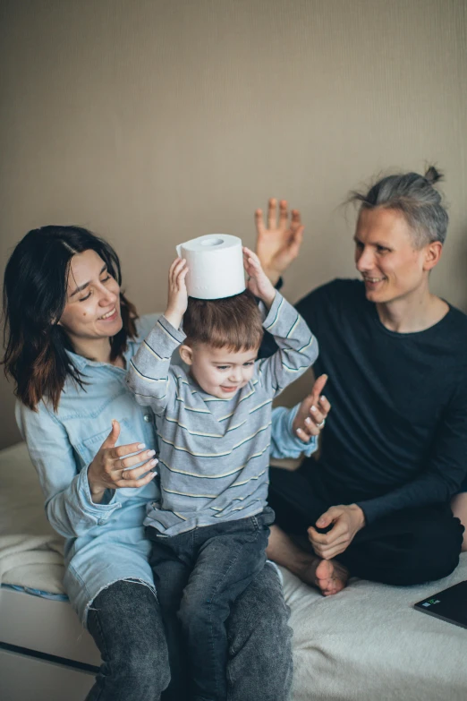 a woman and two children sitting on a bed, by Adam Marczyński, pexels contest winner, funny hat, toilet paper, halo above head, a handsome