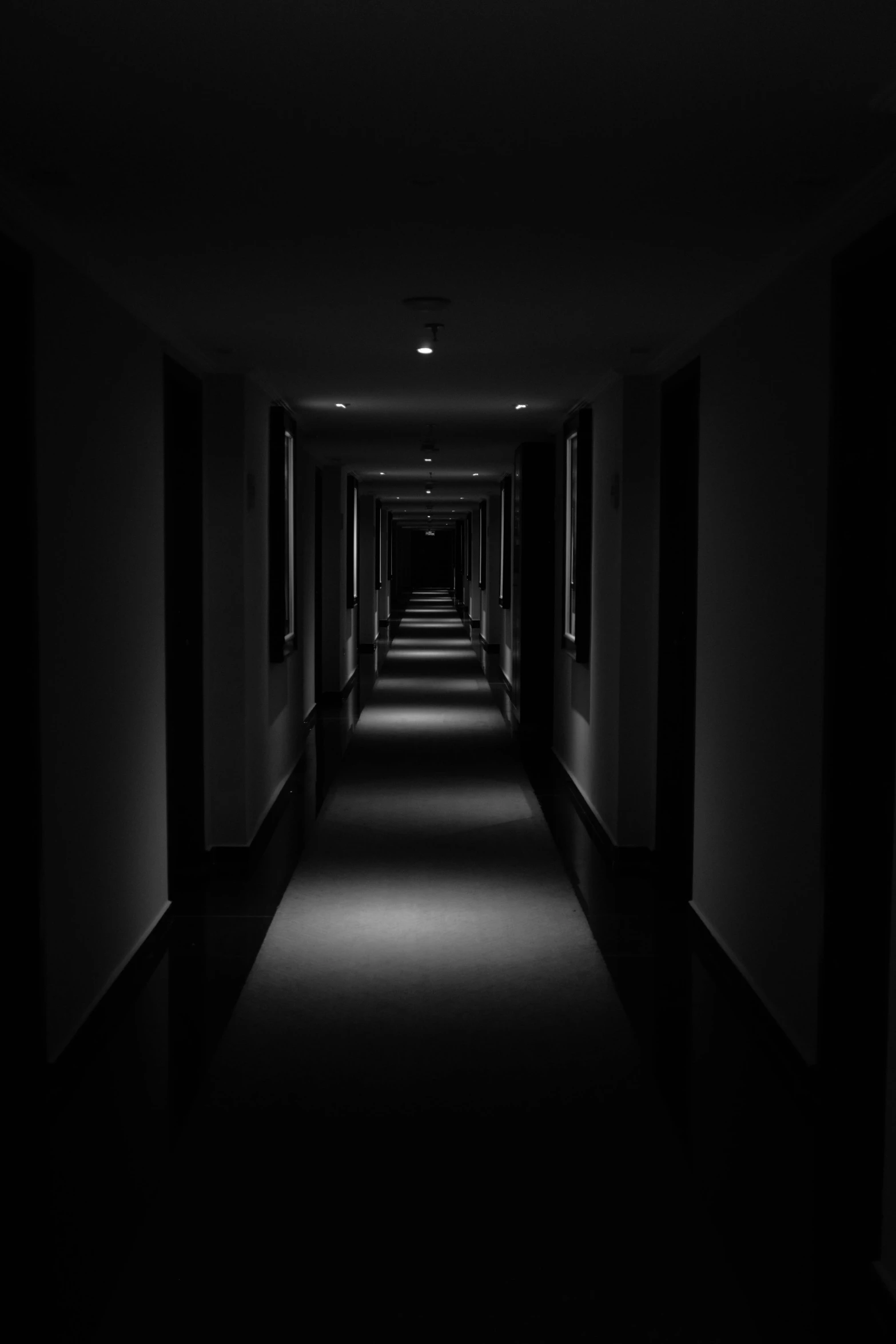 dark corridor leading to another room with black and white pos