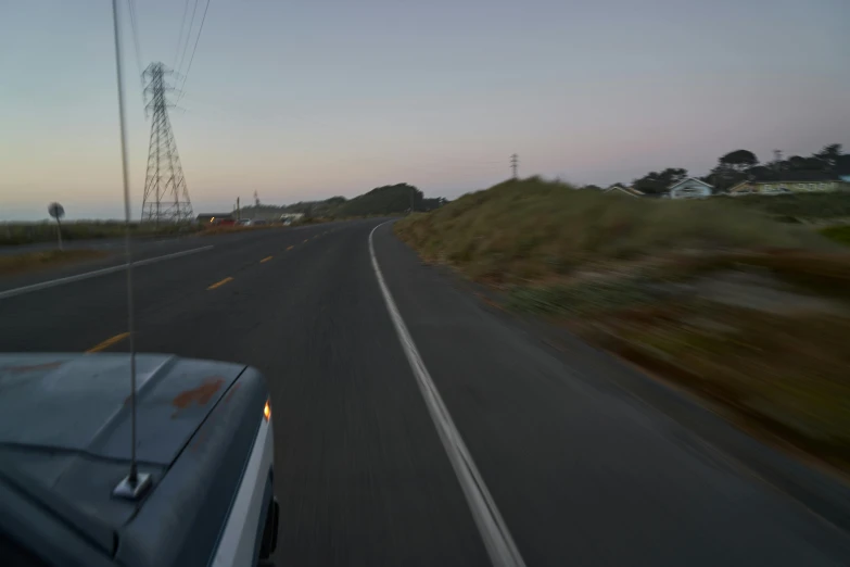 an interstate road during sunset with a truck and cell tower in the background