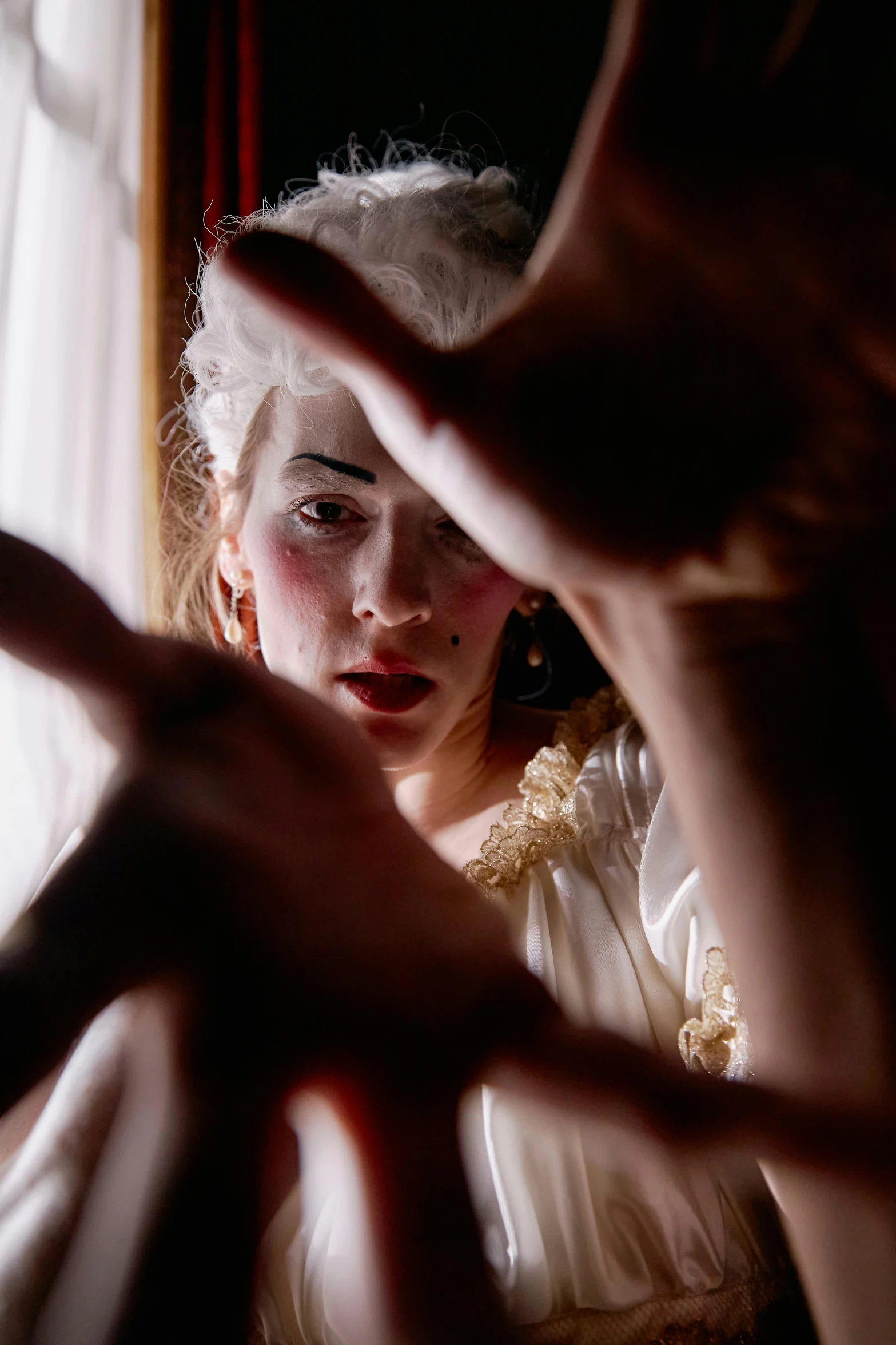 two woman making gestures in front of a mirror