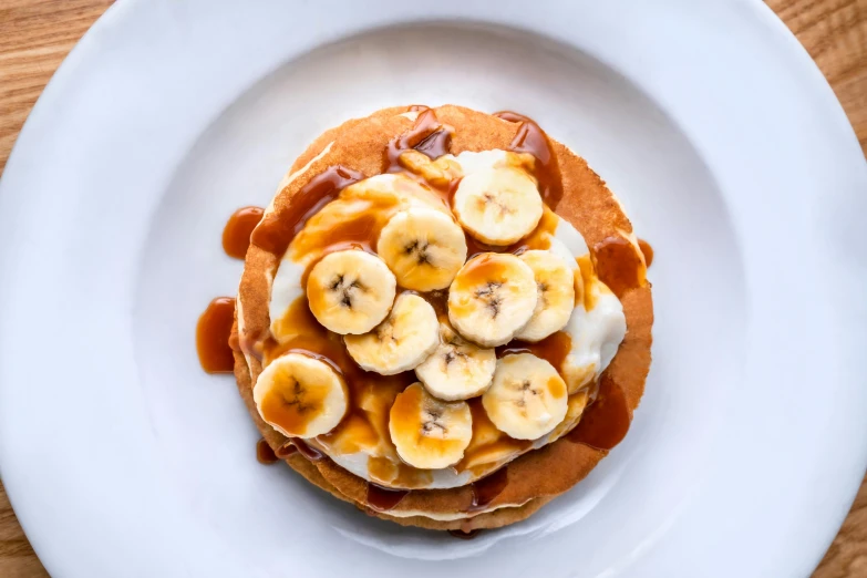 a white plate topped with pancakes covered in banana slices, inspired by Richmond Barthé, trending on pexels, 🦩🪐🐞👩🏻🦳, gif, london, 1 1 1 1