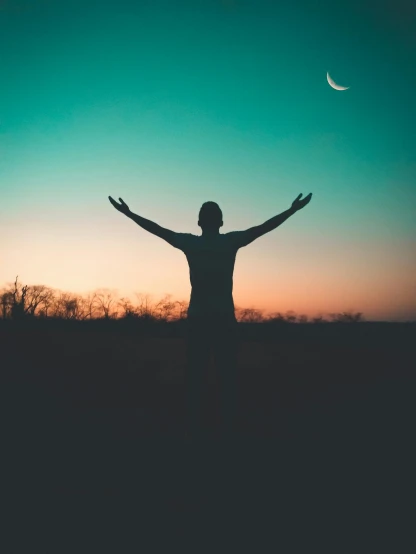 a man standing on top of a grass covered field, pexels contest winner, symbolism, crescent moon in background, pose(arms up + happy), predawn, profile picture
