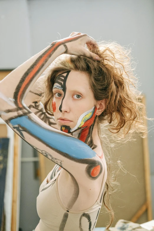 a woman that is standing in front of a mirror, an album cover, inspired by Elizabeth Polunin, trending on pexels, tribal facepaint, patricia piccinini, portrait of a female art student, body paint