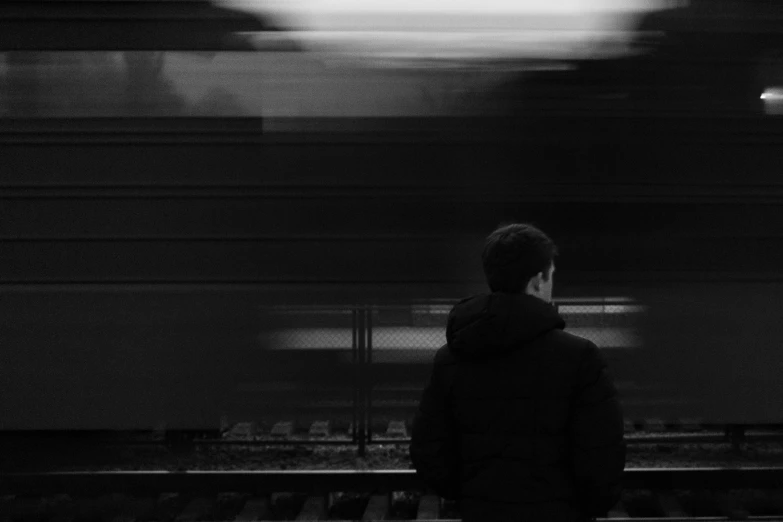 a black and white photo of a man standing in front of a train, a black and white photo, by Karl Buesgen, pexels contest winner, minimalism, motionb blur, faceless people dark, video still, people watching