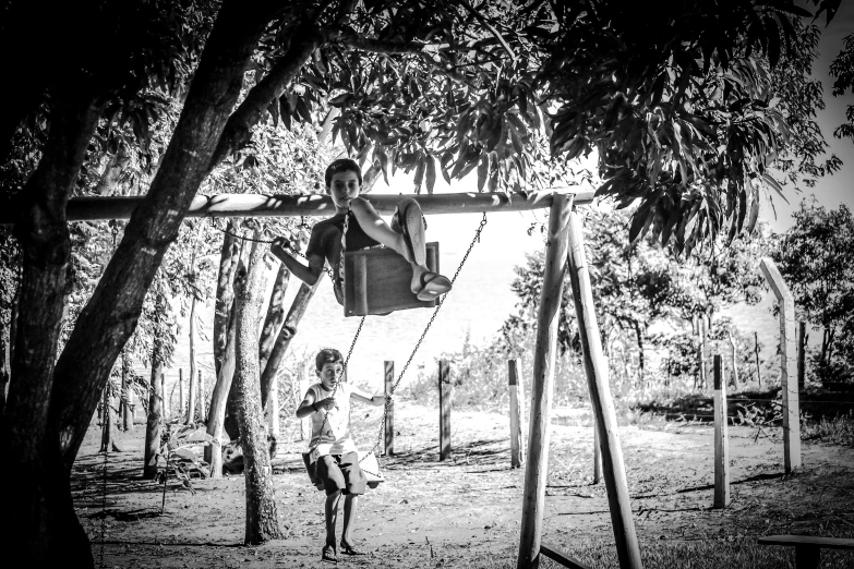 a black and white photo of two children on a swing, a black and white photo, pexels contest winner, eyelevel!!! view!!! photography, monochrome hdr, childhood friend, amidst nature