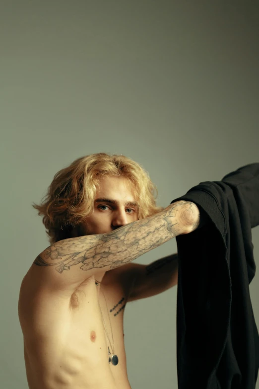 a shirtless man holding a black shirt over his shoulder, a tattoo, inspired by Seb McKinnon, trending on pexels, pale skin curly blond hair, clemens ascher, timothee chalamet, 90s photo