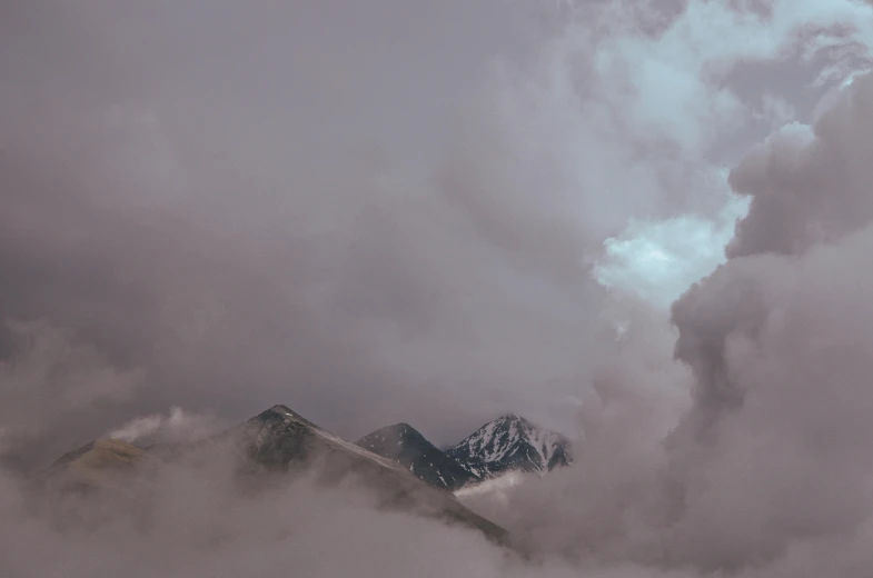 an airplane is flying above a cloudy mountain