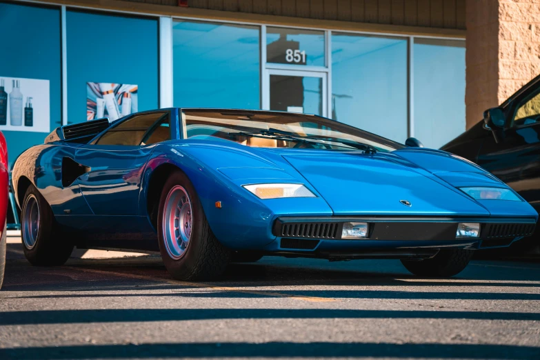 a blue sports car is parked outside a business