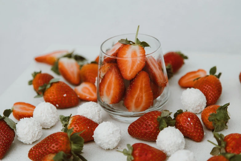 a glass filled with lots of strawberries on top of a table, orange and white, background image, candy treatments, thumbnail