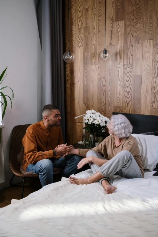 an old woman sitting in her bed as a man sits on the bed