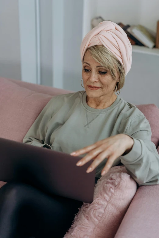 a woman sitting on a couch using a laptop, trending on pexels, renaissance, wearing a turban, aging, thumbnail, ( 3 1