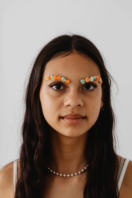 a woman with flowers on her eyes, a colorized photo, trending on pexels, orange pupils, made out of sweets, isabela moner, symetrical detailed faces