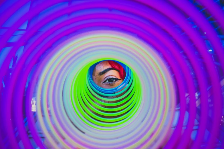 a close up of a person looking through a circular object, an album cover, inspired by David LaChapelle, pexels contest winner, psychedelic art, rainbow tubing, spiral eyes, purple tubes, stood in a tunnel