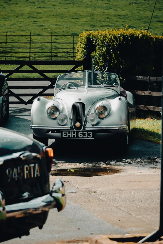 the old sports car is parked by the gate