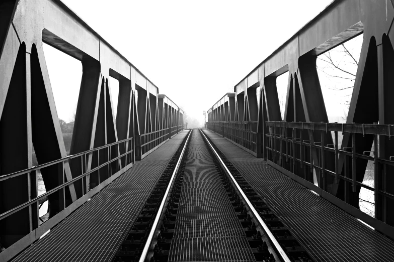 a black and white photo of a train track, a black and white photo, pexels contest winner, minimalism, metallic bridge, in empty!!!! legnica, symmetrical realistic, early in the morning