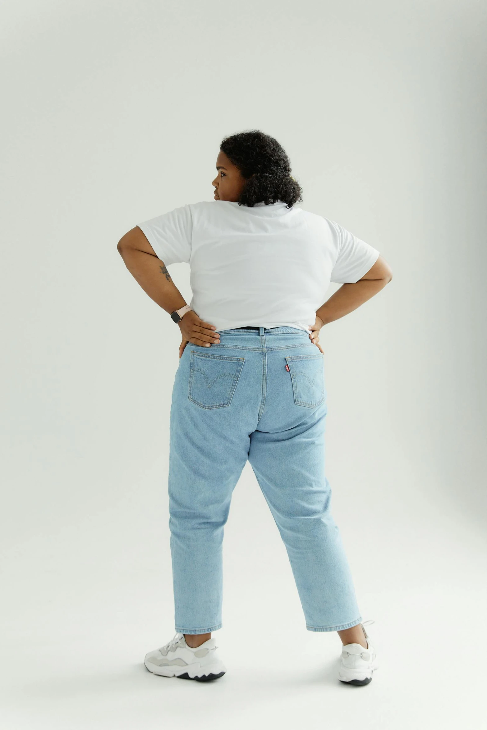 a woman in jeans and heels standing looking back