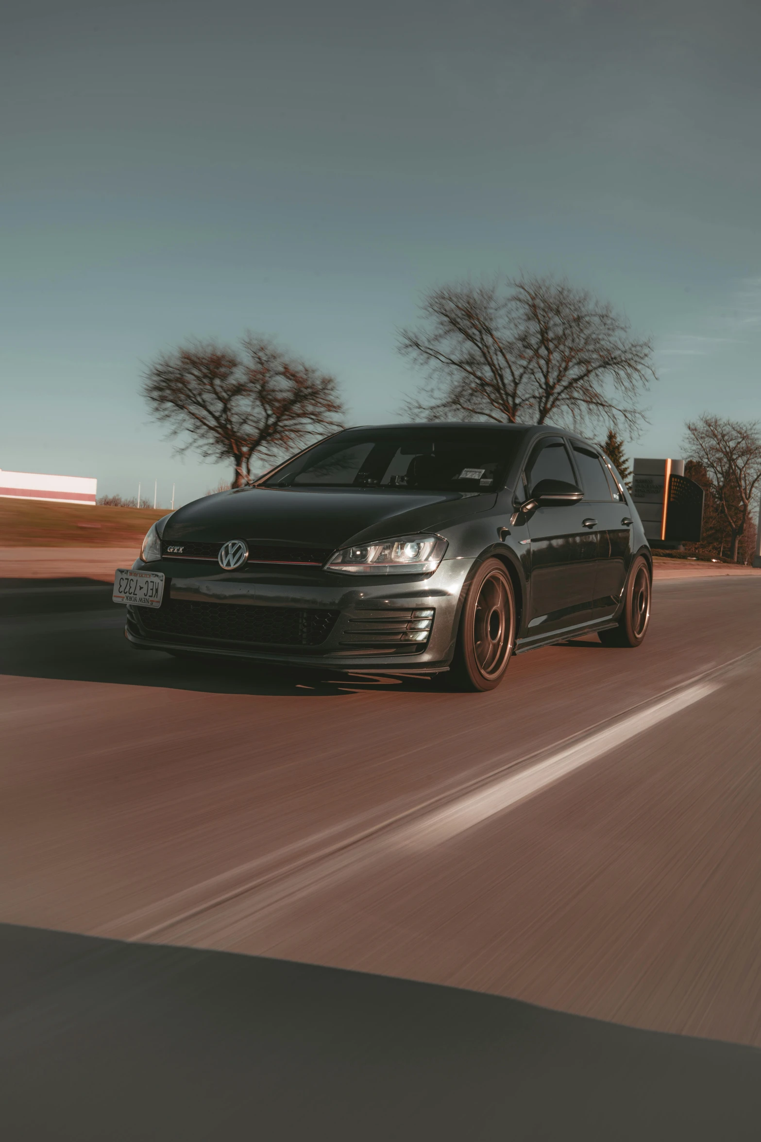 a black car driving down a road with trees in the background, golden hour 8k, 15081959 21121991 01012000 4k, aggressive stance, a 35mm photo